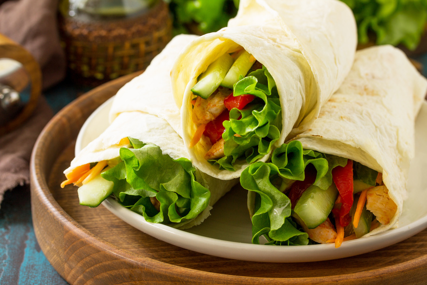 Healthy lunch snack. Tortilla wraps close-up with grilled chicken and  fresh vegetables on blue table. Chicken Tortilla, mexican street fast food.